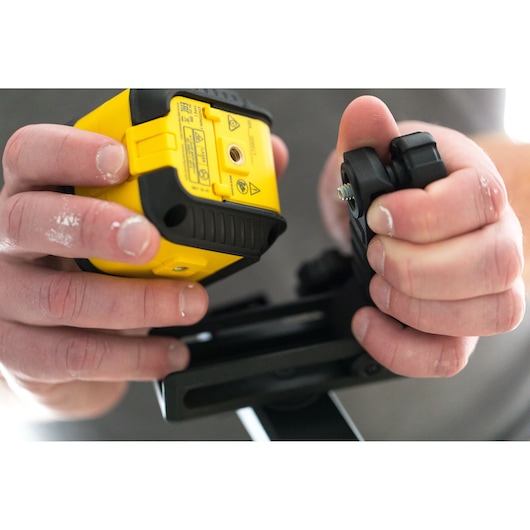 STANLEY STHT77498-1 photography close-up of hands assembling yellow laser level device and black mount