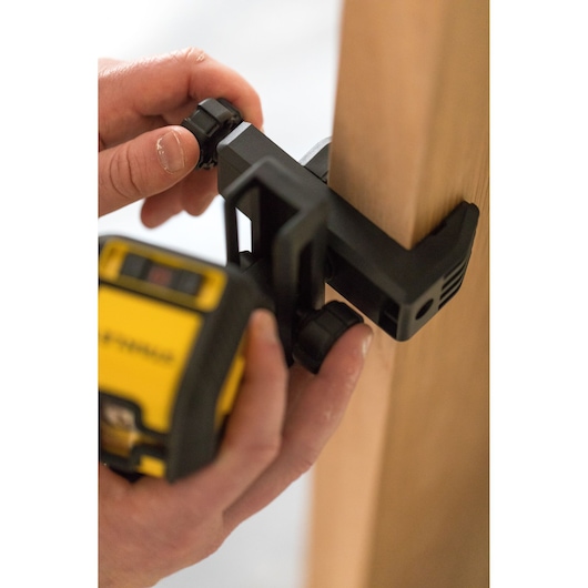 STANLEY STHT77498-1 laser level being mounted on a wooden surface by hand, close-up photography.