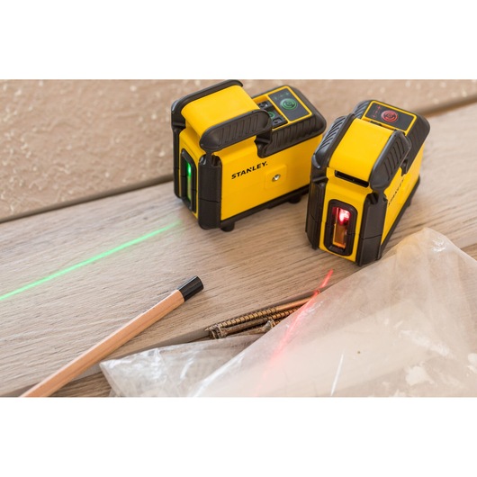 STANLEY STHT77594-1 laser level devices on wood surface, emitting green and red lines, photography close-up.