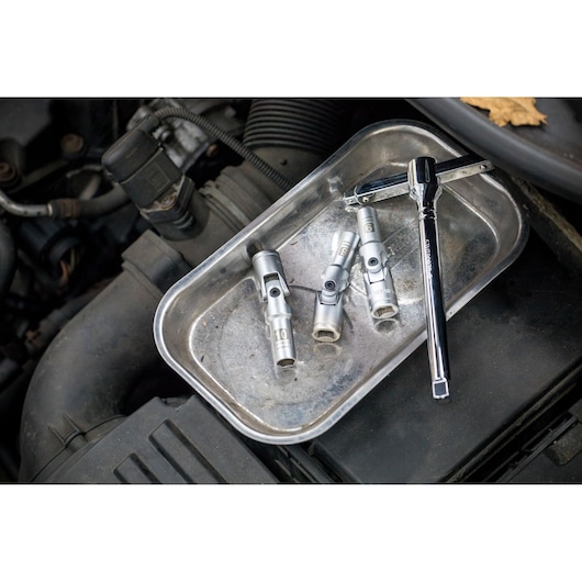 STANLEY STHT80888-0 socket wrench and three sockets in metal tray on car engine.
