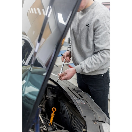 STANLEY STHT80888-0 photography of a person using a ratchet wrench on a car engine, front angle.