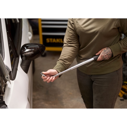 STANLEY STHT80890-0 torque wrench in use near car door, person holding tool by black handle.
