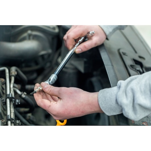 Photo of STANLEY STHT81015-0 ratchet being used to remove a spark plug in an engine bay.
