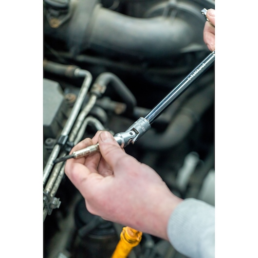 STANLEY STHT81015-0 socket wrench used to remove a spark plug in automotive repair, photo close-up.