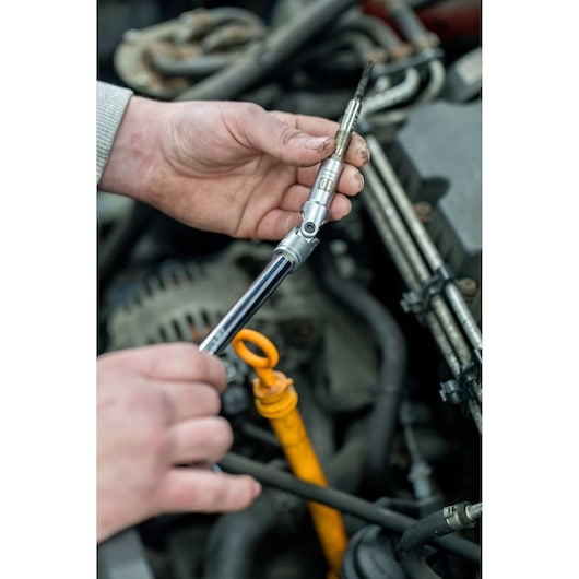 STANLEY STHT81016-0 socket wrench used in car engine maintenance, close-up of tool in mechanic's hands.