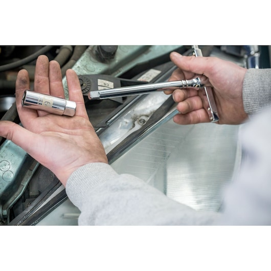 STANLEY STHT81583-0 socket wrench and socket held in hands near car engine, close-up photography.