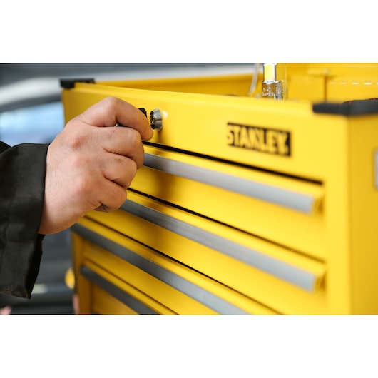 Photo of STANLEY STMT1-75062 yellow tool chest being locked, close-up of hand turning the lock.
