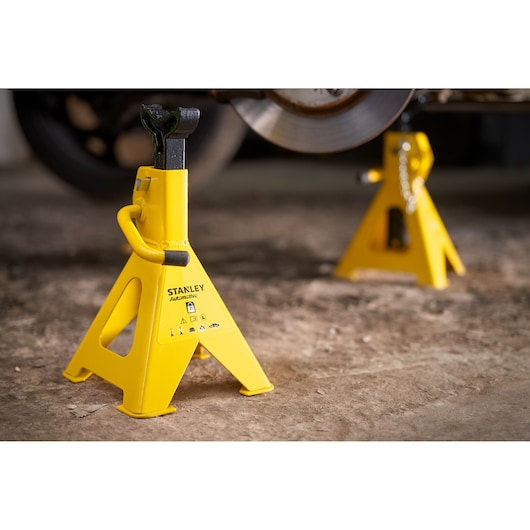 STANLEY STMT81255-1 yellow automotive jack stand side angle on workshop floor.