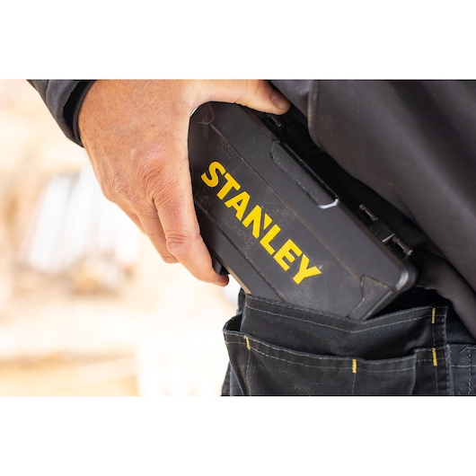 Photo of a hand placing a STANLEY STMT82672-0 black tool case into a tool belt pouch, close-up view.