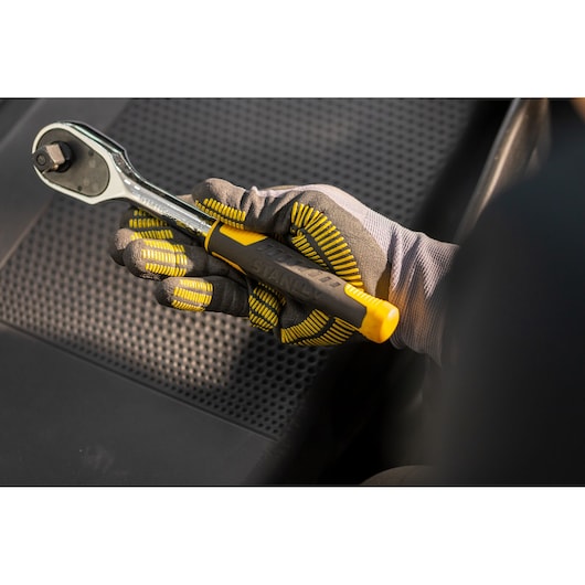 STANLEY STMT82830-1 ratchet wrench with yellow and black handle held in gloved hand, photography close-up.