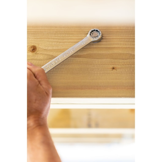 STANLEY STMT82843-0 wrench being used on a bolt in light wood, close-up photography.