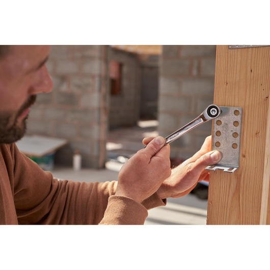 Photo of STANLEY STMT82846-0 flat ratcheting wrench used on metal bracket on wooden beam during construction.