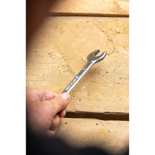 STANLEY STMT82847-0 open-end wrench held in hand on wooden surface, close-up photography.