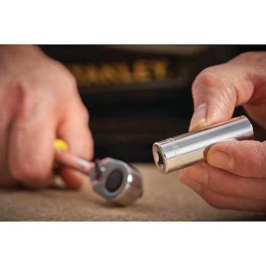 STANLEY STMT86094-0 socket held in hand, close-up with ratchet tool in background.