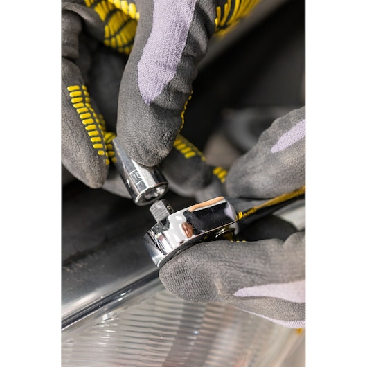 STANLEY STMT86105-0 ratchet wrench and socket held by gloved hands, close-up view.