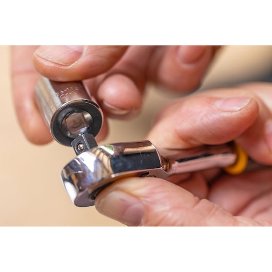 STANLEY STMT86111-0 ratchet wrench close-up with socket attachment in use, photography of hand holding tool.