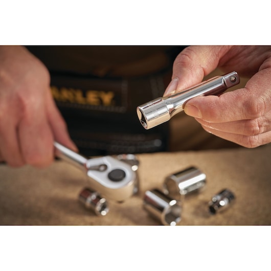 STANLEY STMT86206-0 socket wrench extension held by hand, with ratchet and sockets on workbench.