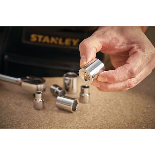 STANLEY STMT86312-0 socket held in hand, several chrome sockets on table, tool bag in background.