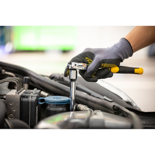 Photo of STANLEY STMT88941-0 ratchet wrench used on car engine, worker wearing gloves.