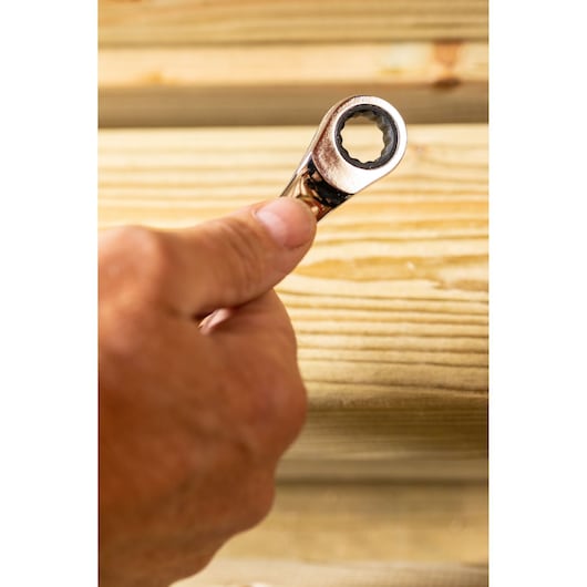 Photo of STANLEY STMT89917-0 ratcheting wrench held in hand near wood surface.