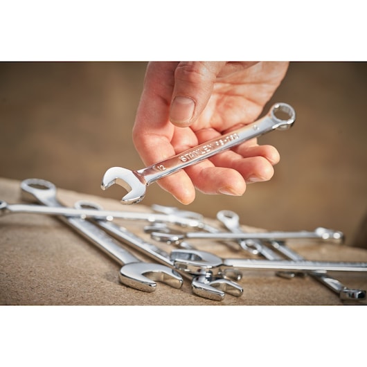 Photo of STANLEY STMT95790-0 combination wrench held in hand, with other chrome wrenches on a workbench.