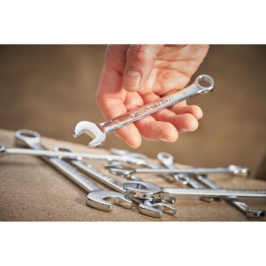 Photo of STANLEY STMT95911-0 wrench held in hand, with other chrome wrenches on a work surface.