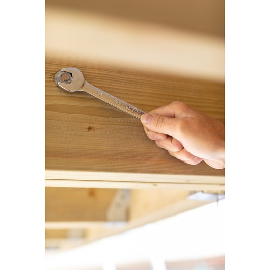 Photo of STANLEY STMT95911-0 combination wrench tightening a bolt on wood beam, product in use.