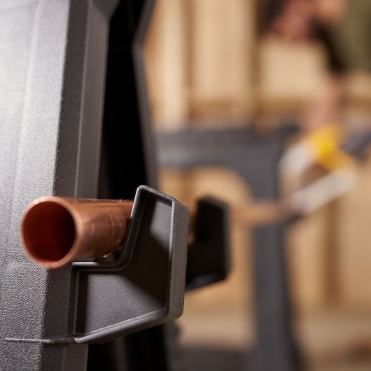 STANLEY STST1-70713 photography of black plastic clamp holding copper pipe, close-up side angle.