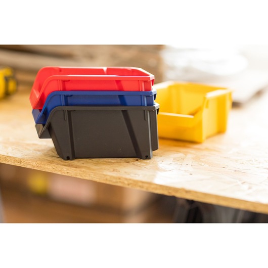 STANLEY STST82736-1 stackable plastic storage bins in red, blue, black and yellow on a wooden surface.
