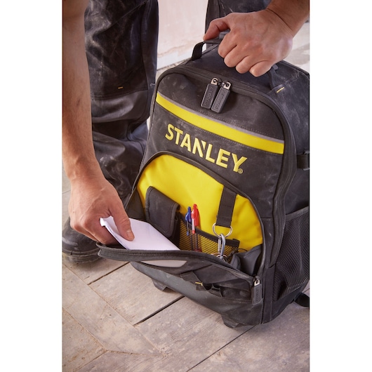 Photo of STANLEY STST83307-1 black and yellow tool backpack with open front pocket showing pens, papers, and tools.