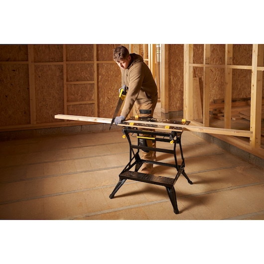 STANLEY STST83800-1 sawhorse used for cutting wood, shown in a construction site setting.