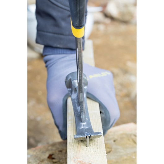 STANLEY XTHT1-51148 claw hammer removing nail from wood, close-up photo of gloved hand in use.